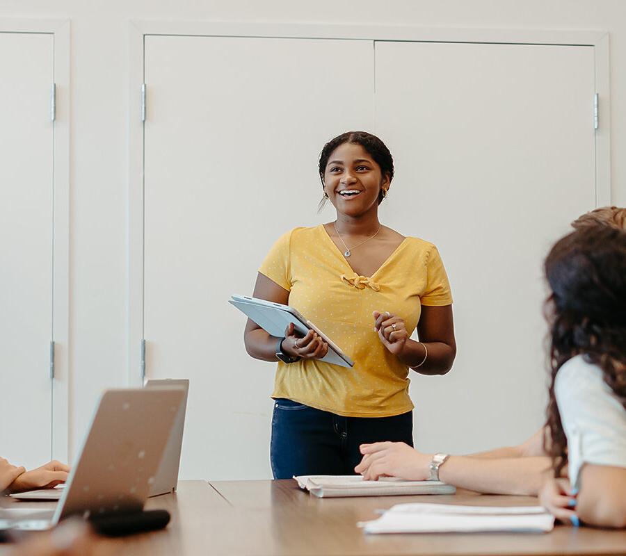 a smiling student presents in class to other students